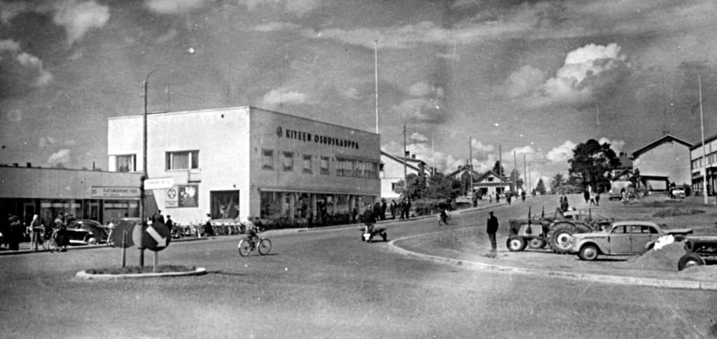 1960-luvulla katukuvaa talo hallitsi vielä Kiteen Osuuskaupan nimellä. Peruskorjattu Kiteentie on kuitenkin jo tunkeutunut aivan kaupan oville.
